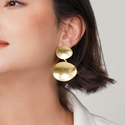 Close-up detail of a gold-plated organic disc earring featuring a matte brushed texture.